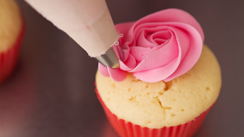piping frosting on cupcake