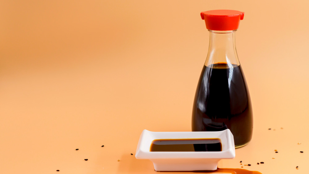 Kikkoman-style soy sauce bottle with red top next to dipping bowl