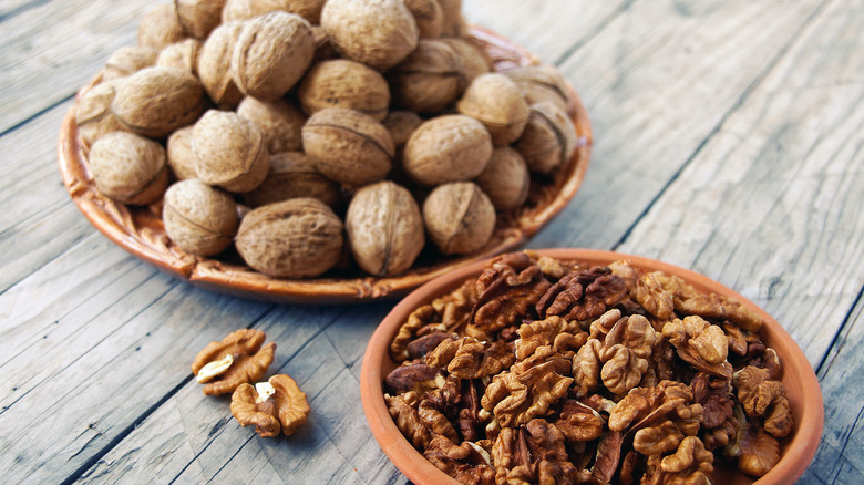 Shelled and unshelled walnuts on wooden surface