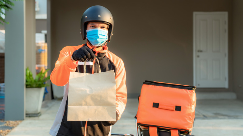 Man with mask holds bag