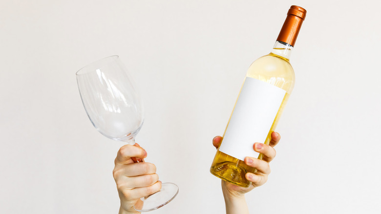 Hand holding a bottle of wine and a glass