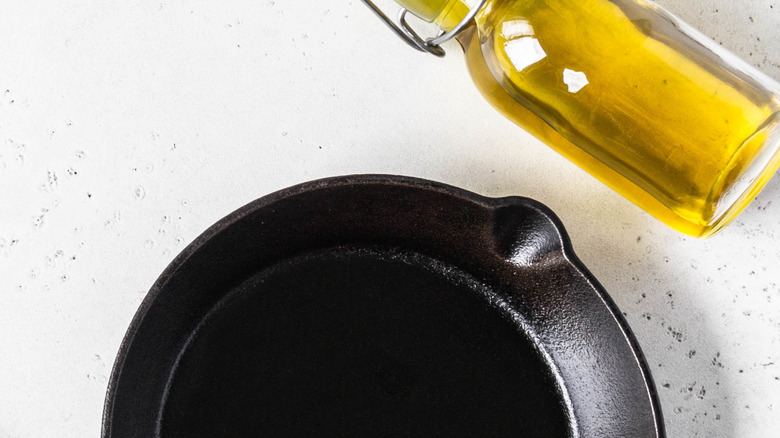 cast iron skillet, wooden spoon and bottle of oil flat lay