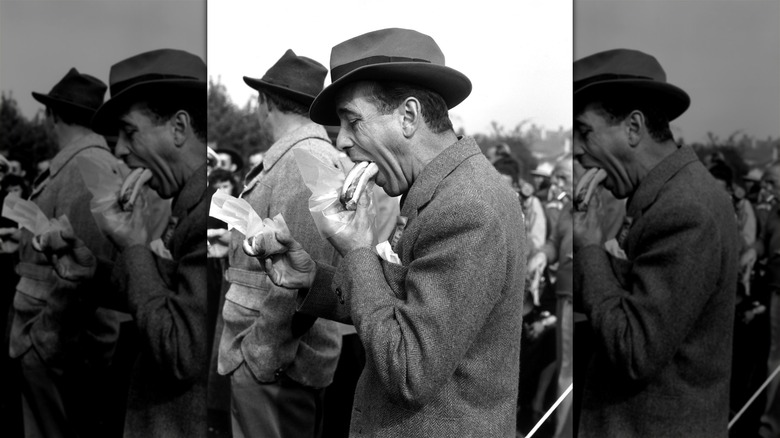 Humphrey Bogart eating a hot dog at a race track.