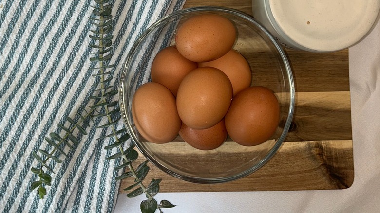 Gray towel, greenery, and brown eggs in a glass bowl