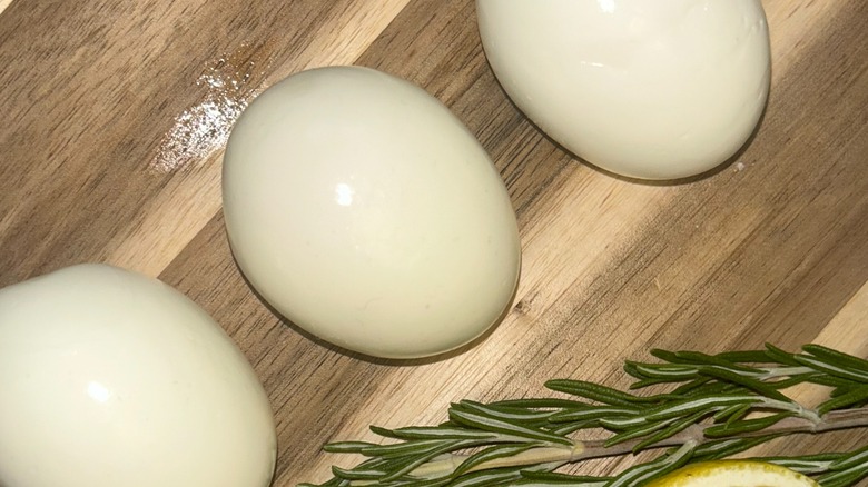Three eggs on wooden board with rosemary