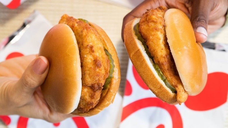 holding two Chick-fil-a chicken sandwiches