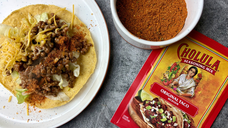 Cholula Original Medium Taco Seasoning Mix packet, seasoning in a white ramekin, and taco on a white plate
