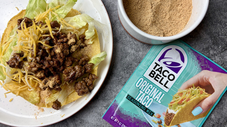 Taco Bell Original Taco Seasoning Mix packet, seasoning in a white ramekin, and a taco on a white plate