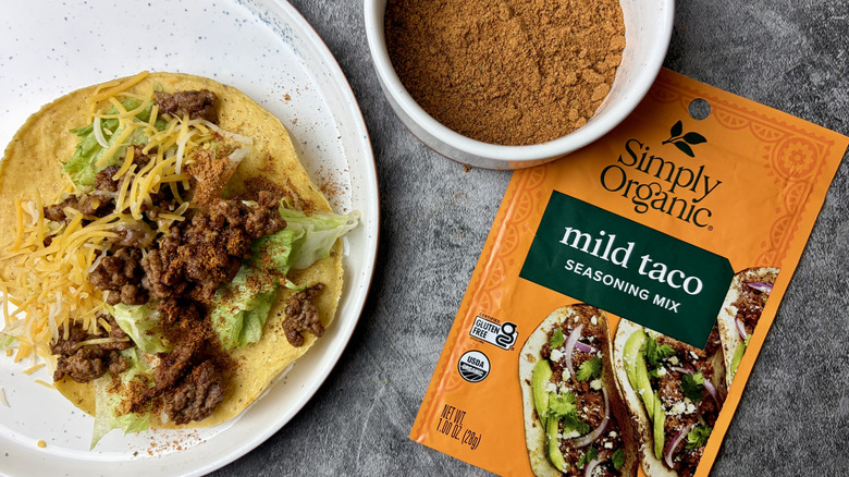 Simply Organic Mild Taco Seasoning Mix packet, seasoning in a white ramekin, and a taco on a white plate