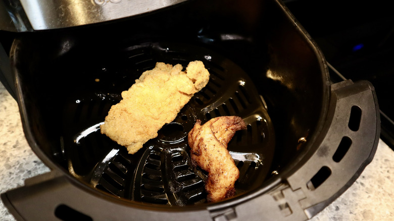 two chicken tenders in an air fryer basket