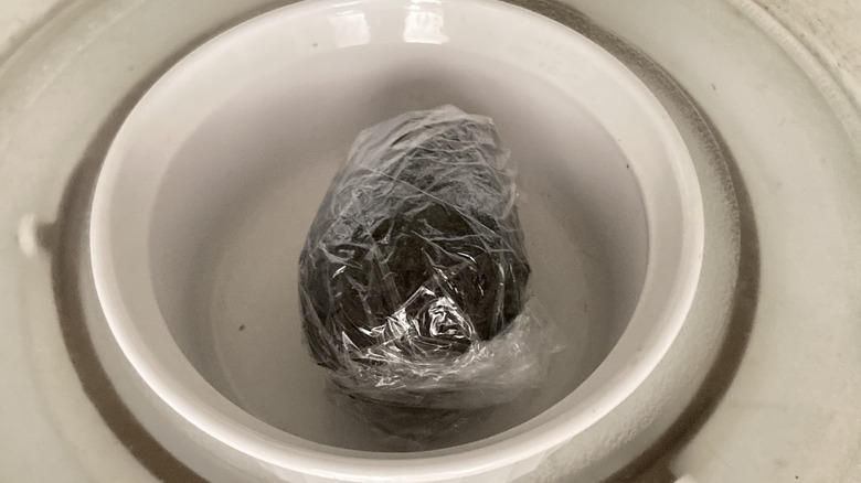 An avocado in plastic wrap in the microwave