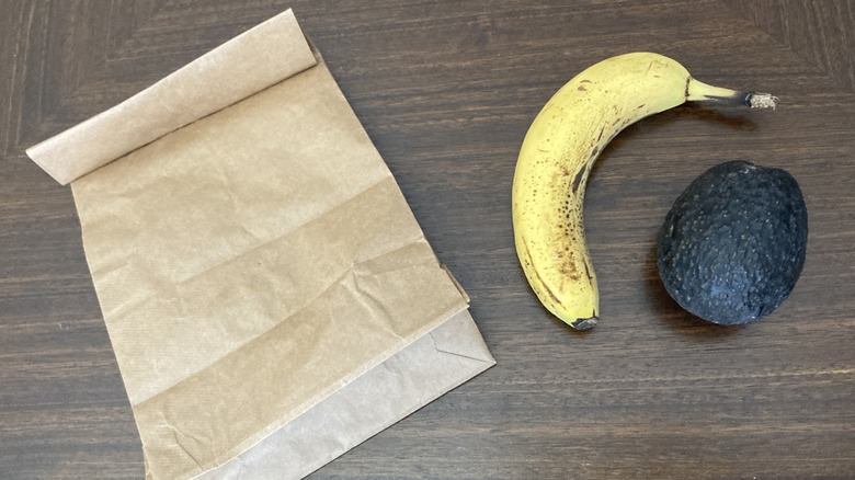 An avocado and a banana next to a paper bag
