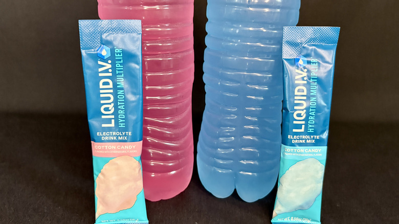 two pink and blue water bottles with Liquid IV packets in front