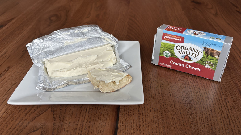 Opened cream cheese block with bagel spread with cream cheese on top