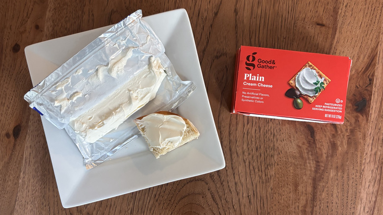 Cream cheese brick with box next to it and bagel with cream cheese spread on top