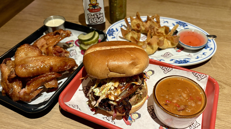 barbecue sandwich, wings, beans, and fried wontons on plates