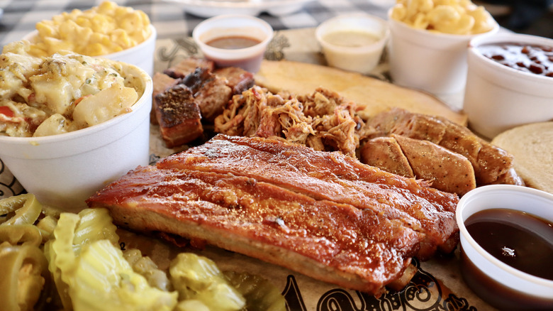 close up of tray filled with barbecue ribs, sides, and pickles