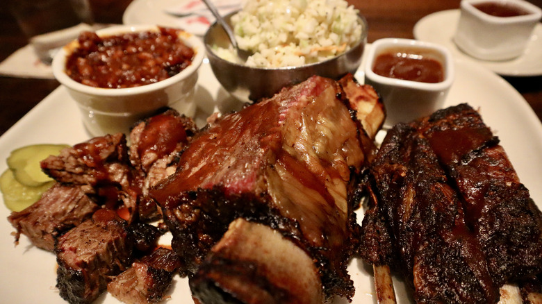 close up of ribs on a plate with sides in background