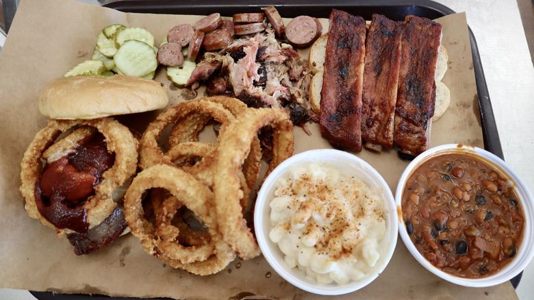 barbecue tray featuring ribs, sandwich, beans, onion rings, and mac and cheese