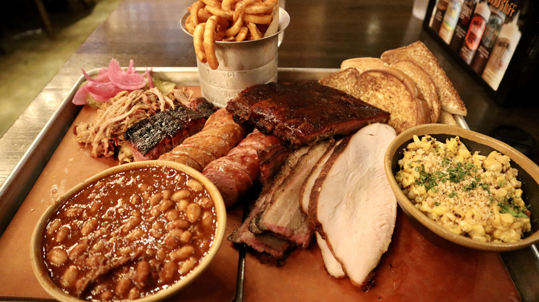 tray of barbecue featuring ribs, corn, beans, and more