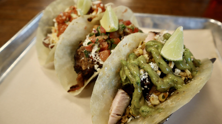 three lime-topped tacos standing on tray