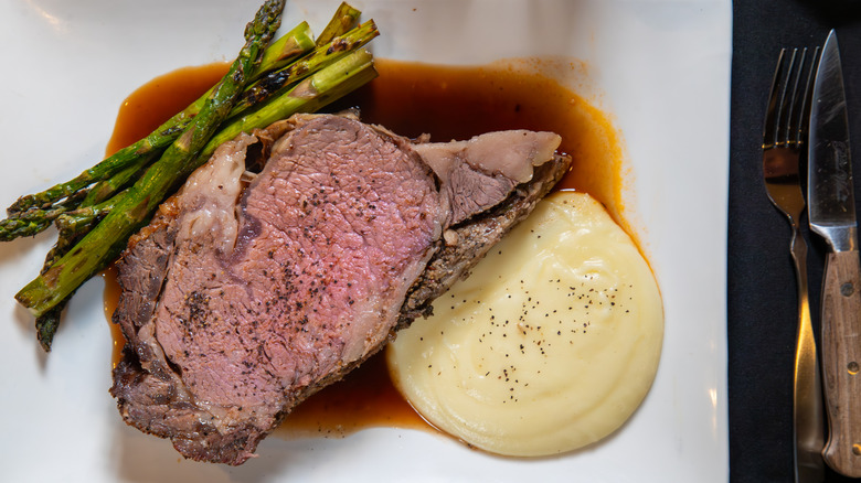 Prime rib with asparagus, mashed potatoes, knife, and fork