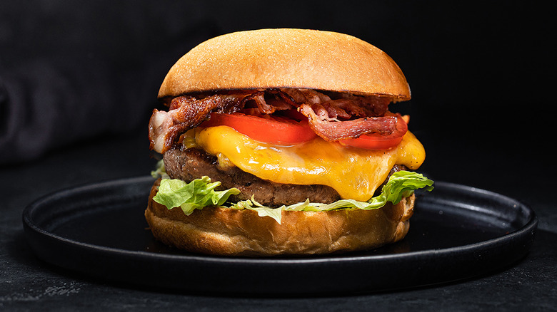 Cheeserburger with bacon on black plate