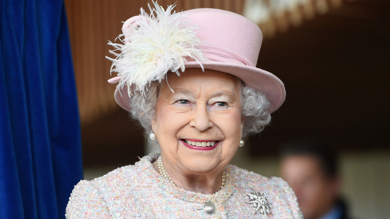 Queen Elizabeth smiling wearing pink sweater and pink hat