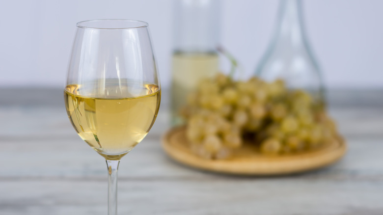 Glass of white wine with grapes in the background