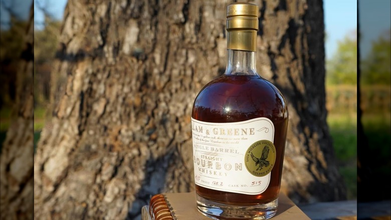 Bottle of Milam & Greene on notebook in front of tree