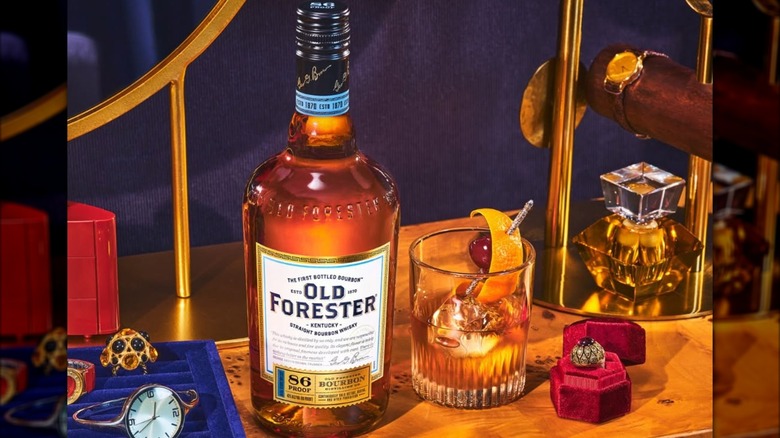 Bottle of Old Forester 86 with cocktail and watches