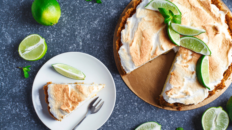 Key lime pie sliced next to whole and halved limes