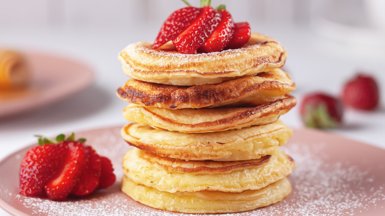 Fluffy pancakes with strawberries and powdered sugar