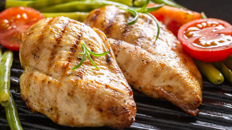 Grilled chicken next to a red tomato