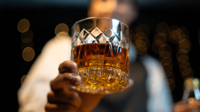 Bartender holding glass of whiskey.