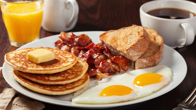 breakfast plate with pancakes, eggs, bacon and toast