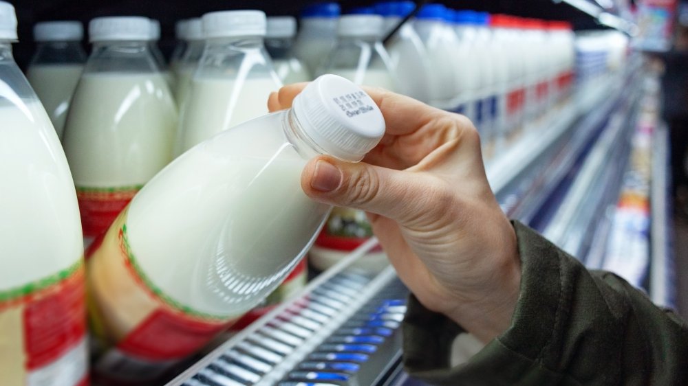 woman's hand pulling milk from store shelf