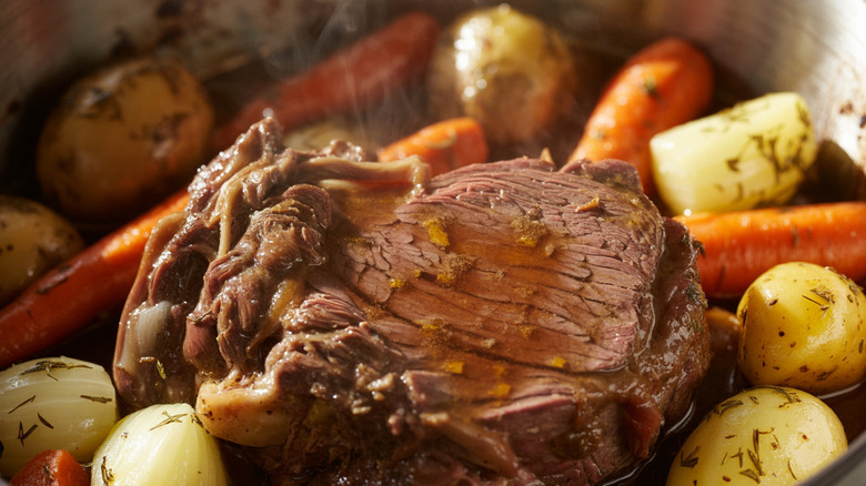 A perfectly slow-cooked pot roast surrounded by potatoes and carrots