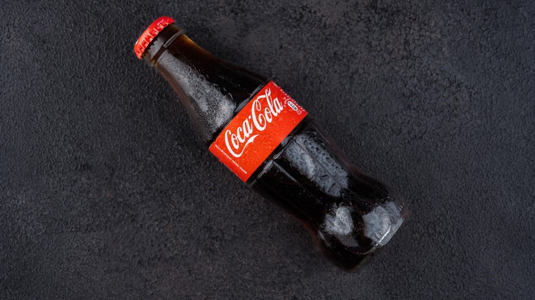 bottle of Coca-Cola tipped over on flat, dark surface