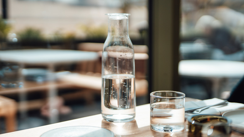 carafe and glass of water on a table at outdoor restaurant