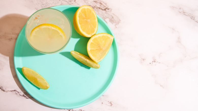 lemonade and lemon slices sitting on a teal blue plate and shown from above