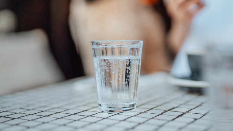 glass of soda water sits on a tiled surface