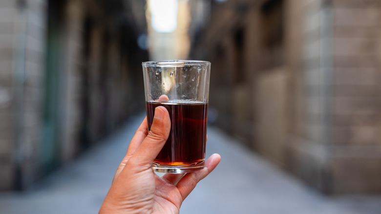glass of vermouth being held in a hand