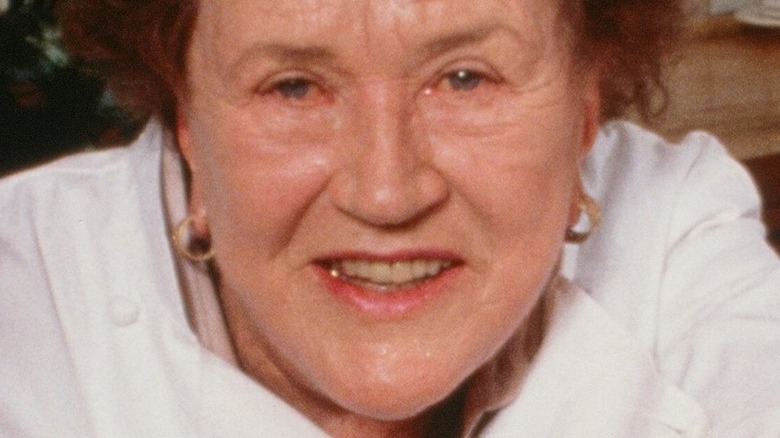 Julia child smiling in front of vegetables and casserole