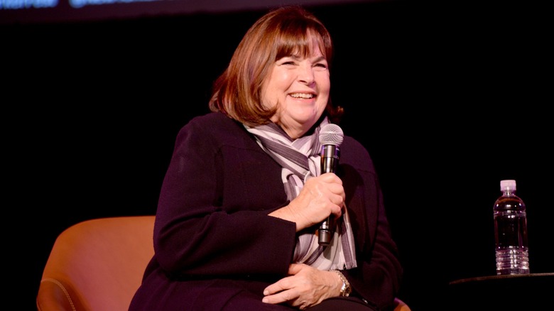 Ina Garten smiling and holding a microphone at a speaking event
