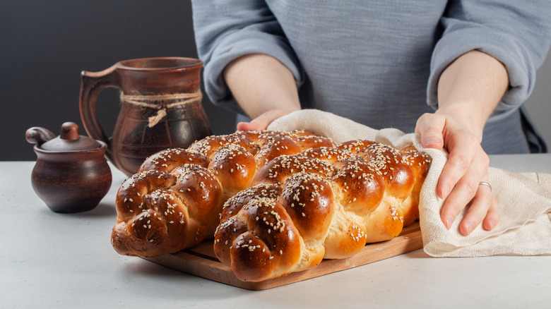 Woman presenting loaves of challah on wooden board