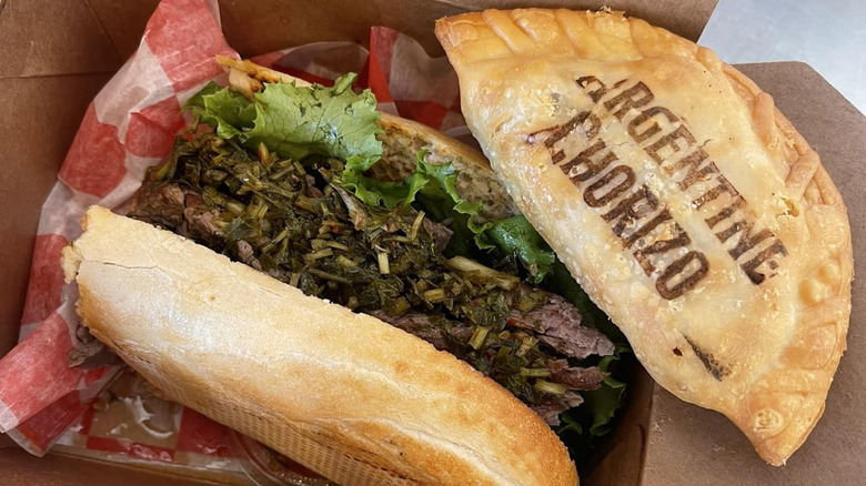 Sandwich topped with steak and chimichurri and empanada stamped with Argentine Chorizo from Che Chori restaurant in Indianapolis, Indiana