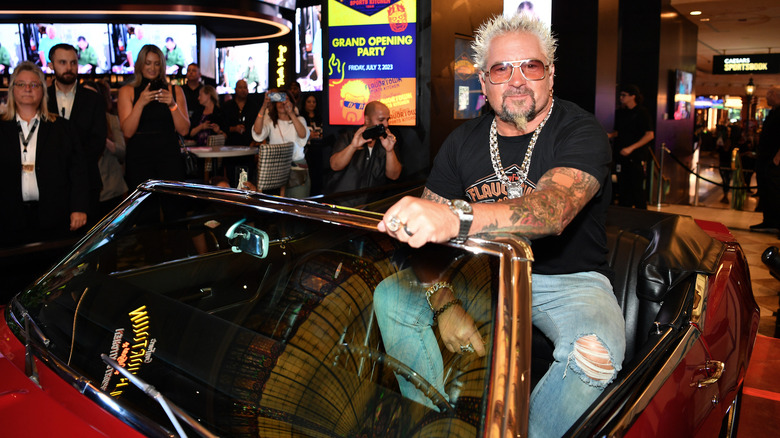 Guy Fieri poses in his iconic red convertible