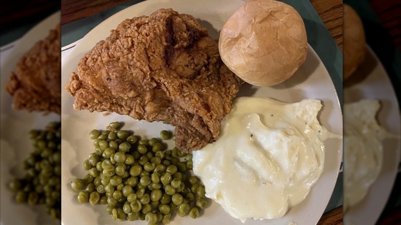 Plate with fried chicken, peas, mashed potatoes, and a dinner roll