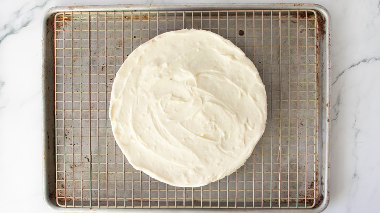 white-frosted cake on a metal rack